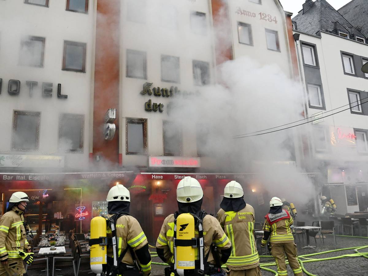 Feuerwehrleute stehen vor einem Gebäude, aus dem dichter Qualm dringt.