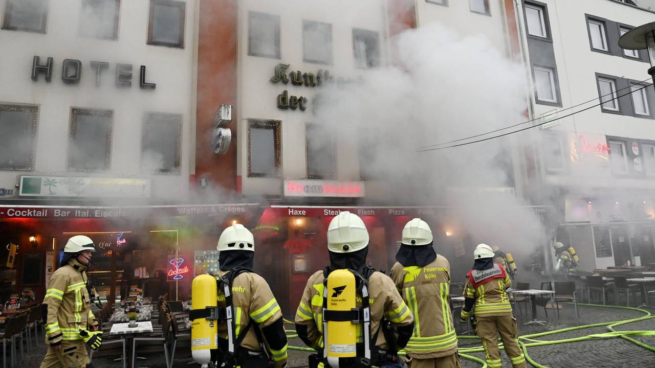 Feuerwehrleute stehen vor einem Gebäude, aus dem dichter Qualm dringt.