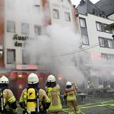 Feuerwehrleute stehen vor einem Gebäude, aus dem dichter Qualm dringt.