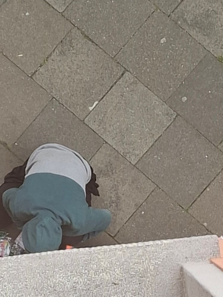 Ein Mann hockt an einer Hauswand und konsumiert Drogen.