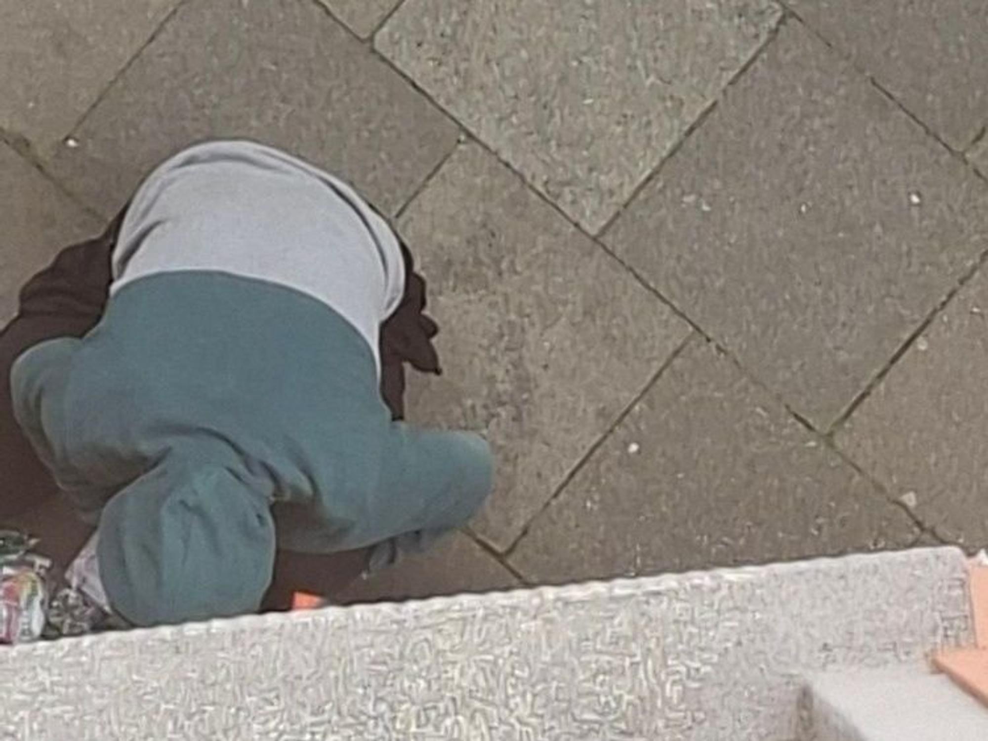 Ein Mann hockt an einer Hauswand und konsumiert Drogen.