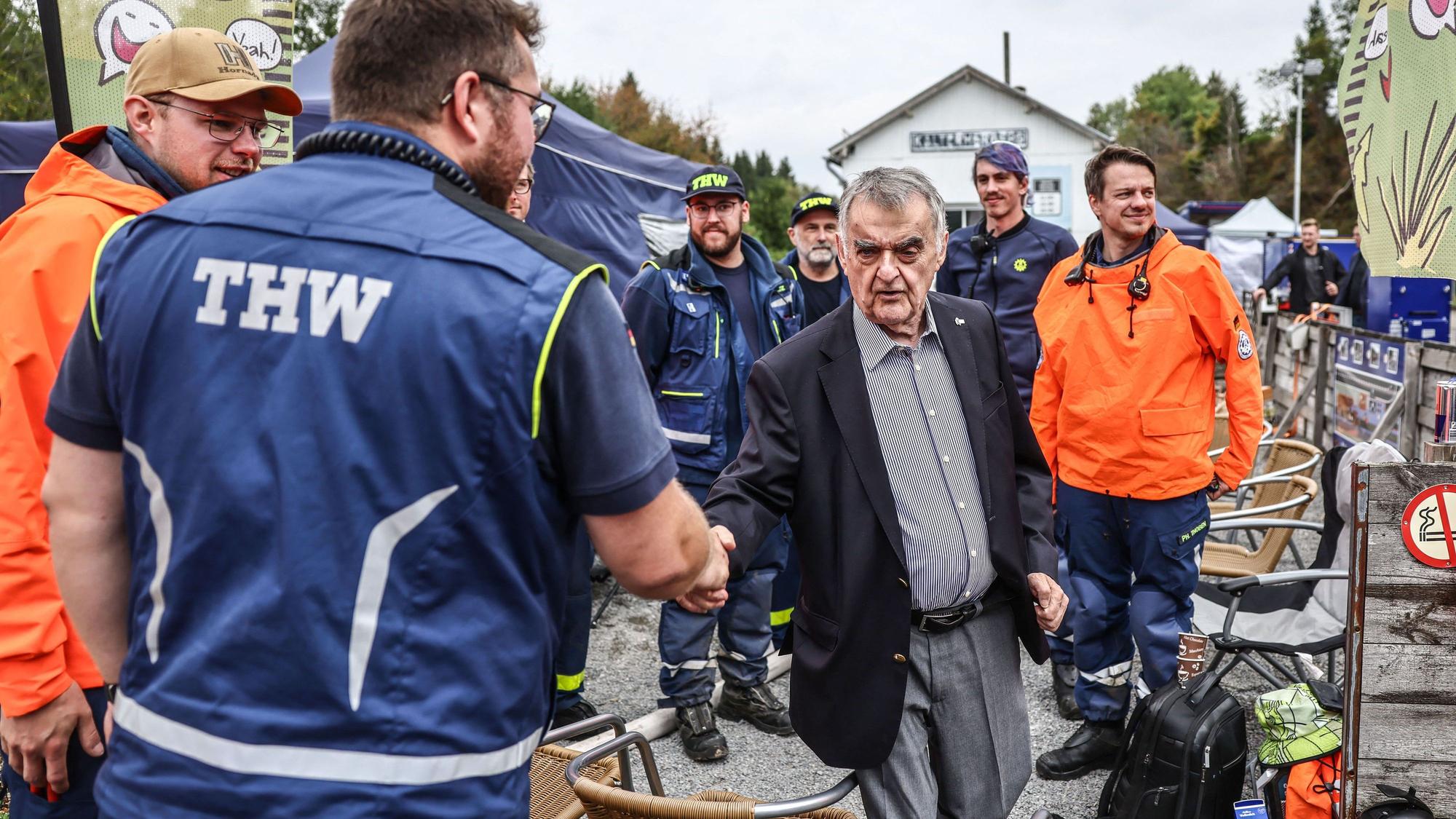 NRW-Innenminister Herbert Reul (Mitte, CDU) spricht mit Helfern des THW an der deutsch-belgischen Grenze an einer Wassertankstation.
