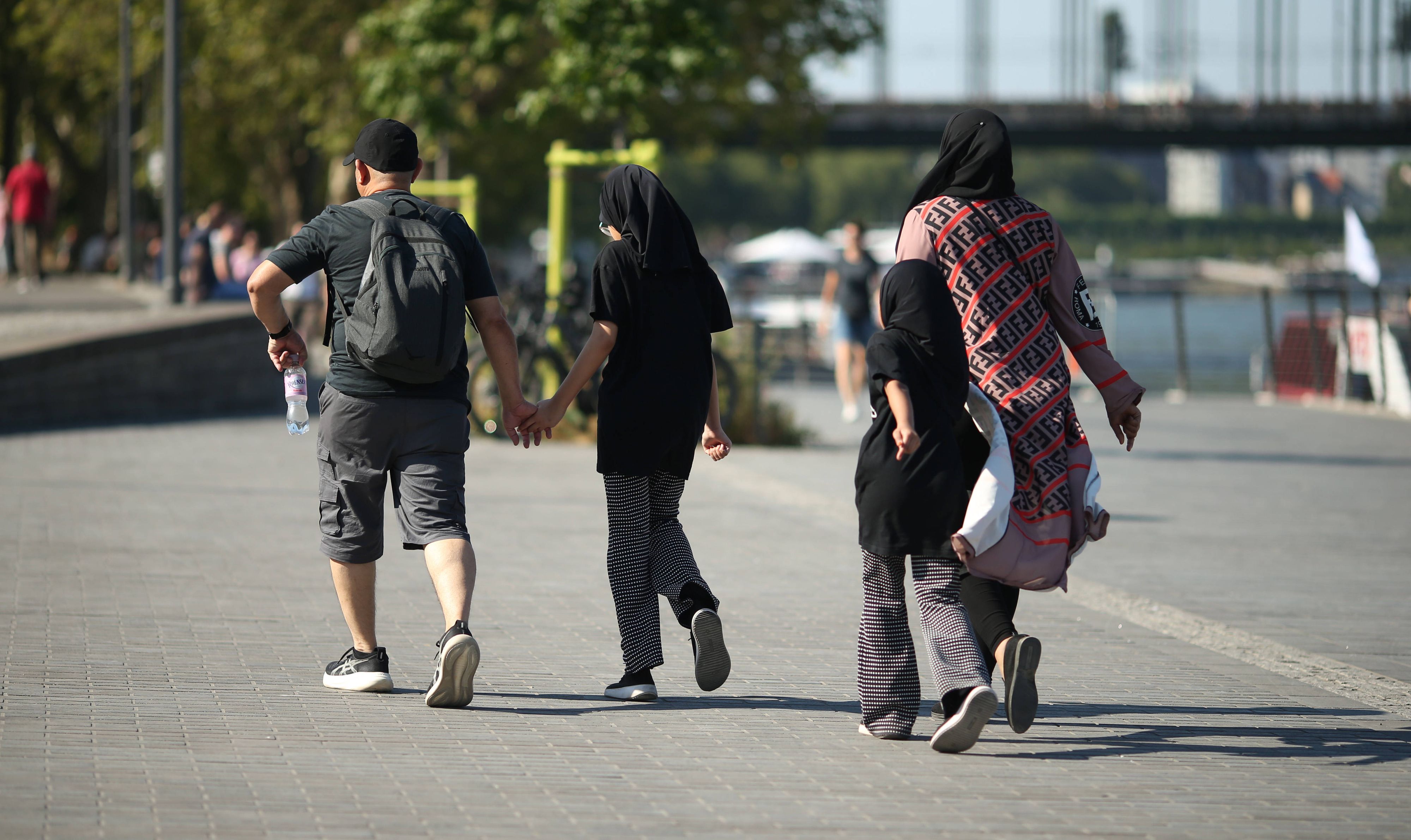 Eine vierköpfige Familie geht am Kölner Rheinufer entlang: Junge Familien zahlen laut einer neuen Erhebung in Köln am meisten für den Alltag.