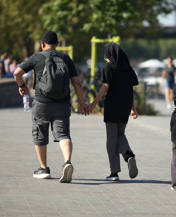 Eine vierköpfige Familie geht am Kölner Rheinufer entlang: Junge Familien zahlen laut einer neuen Erhebung in Köln am meisten für den Alltag.