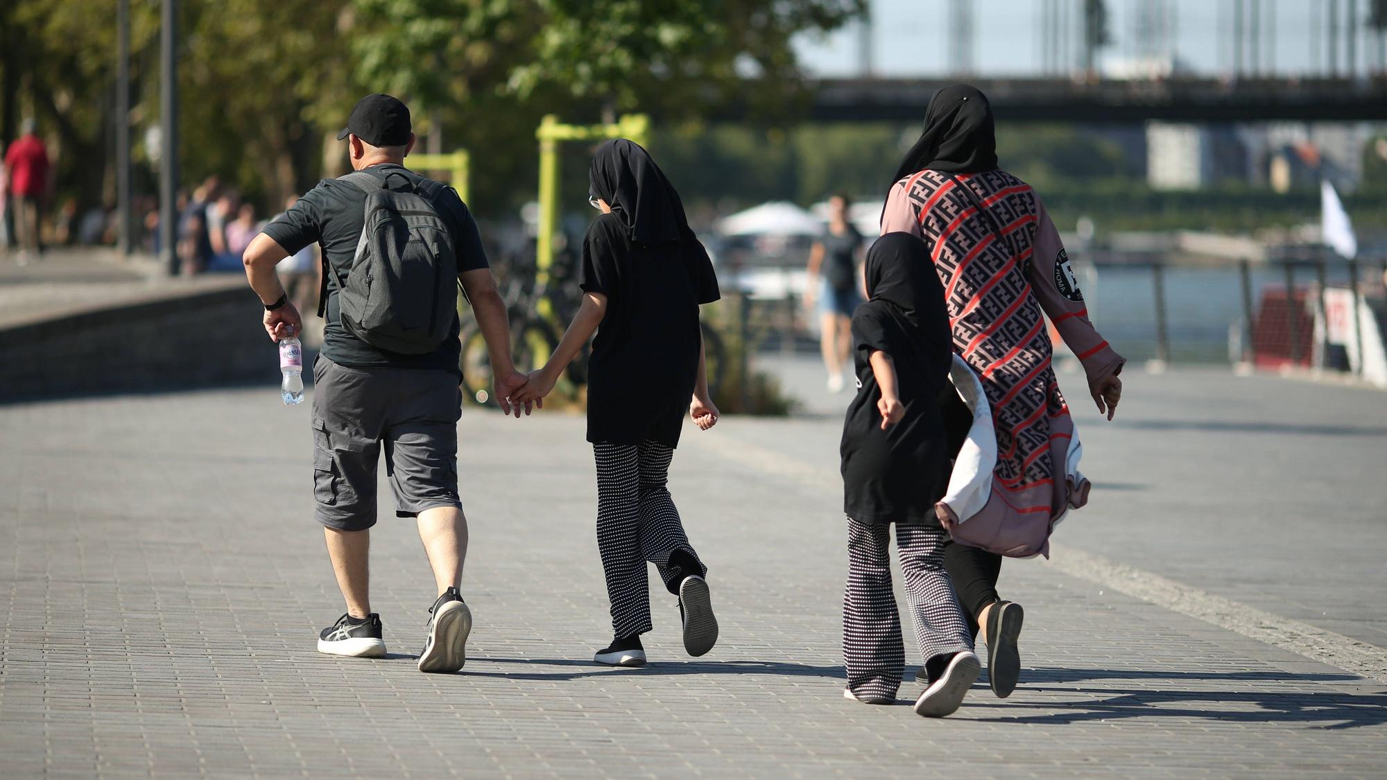 Eine vierköpfige Familie geht am Kölner Rheinufer entlang: Junge Familien zahlen laut einer neuen Erhebung in Köln am meisten für den Alltag.