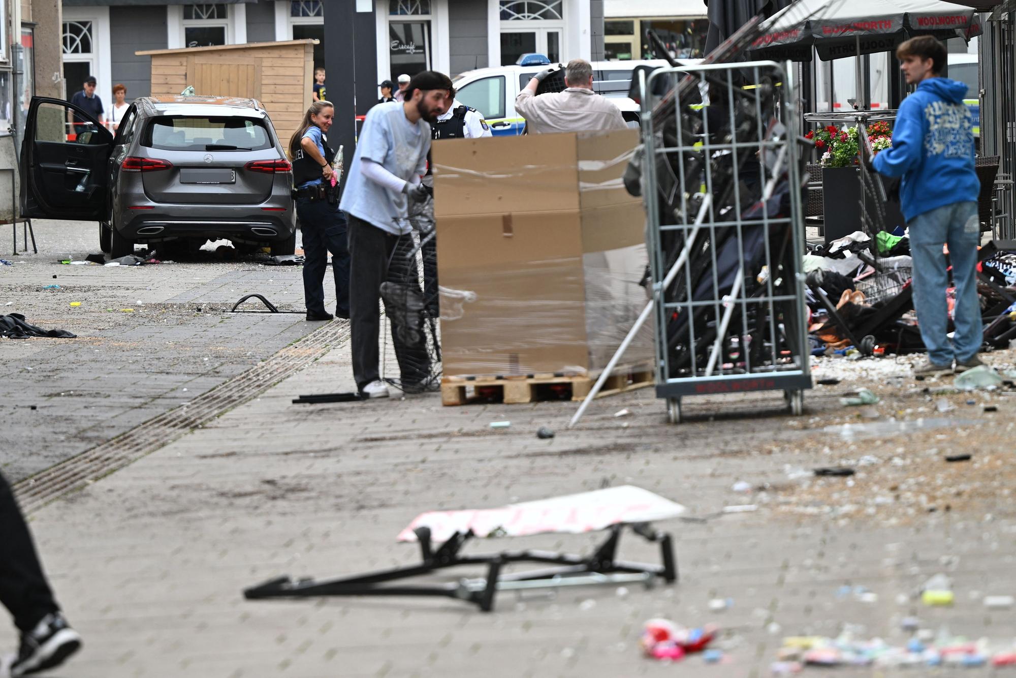 Mitarbeiter eines Geschäfts reinigen die Unfallstelle vor dem Laden. Ein Autofahrer raste am Vormittag mit hoher Geschwindigkeit durch die Fußgängerzone und verletzte dabei mehrere Menschen. Ursache war ersten Erkenntnissen zufolge ein medizinischer Notfall.