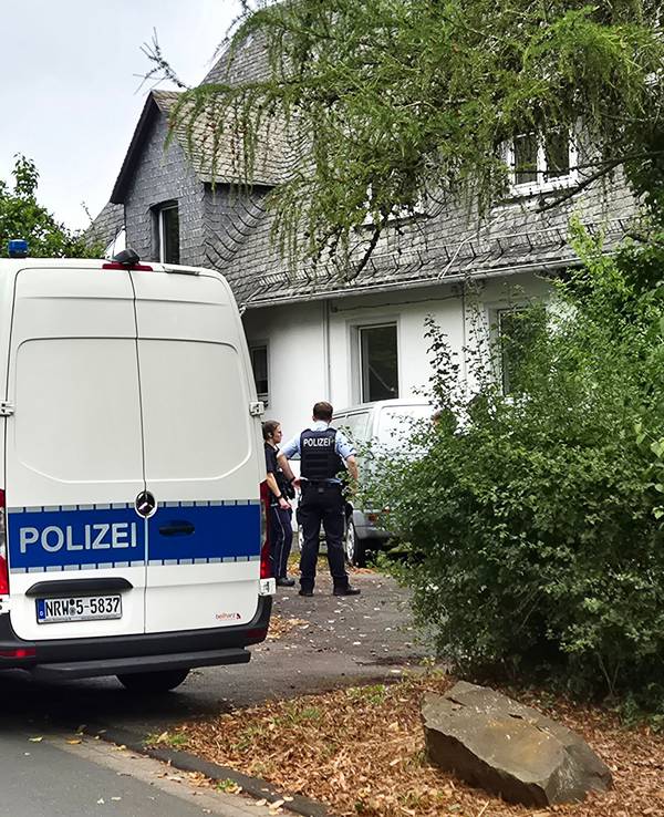 Einsatzkräfte der Polizei stehen vor einem Wohnhaus in Siegen. Die Polizei hat in einer Wohnung die stark verwesten Leichen einer 77-jährigen Frau und eines 55-jährigen Mannes entdeckt.