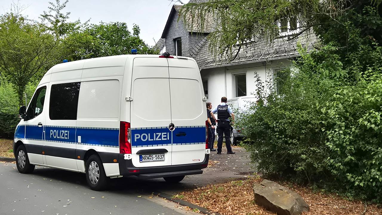 Einsatzkräfte der Polizei stehen vor einem Wohnhaus in Siegen. Die Polizei hat in einer Wohnung die stark verwesten Leichen einer 77-jährigen Frau und eines 55-jährigen Mannes entdeckt.