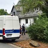 Einsatzkräfte der Polizei stehen vor einem Wohnhaus in Siegen. Die Polizei hat in einer Wohnung die stark verwesten Leichen einer 77-jährigen Frau und eines 55-jährigen Mannes entdeckt.