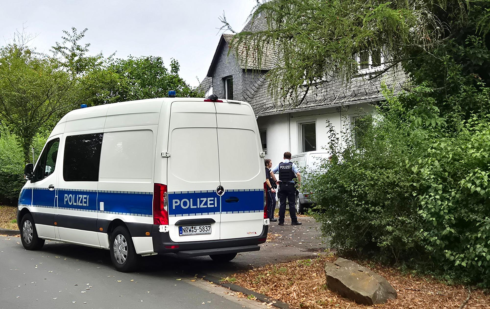 Einsatzkräfte der Polizei stehen vor einem Wohnhaus in Siegen. Die Polizei hat in einer Wohnung die stark verwesten Leichen einer 77-jährigen Frau und eines 55-jährigen Mannes entdeckt.