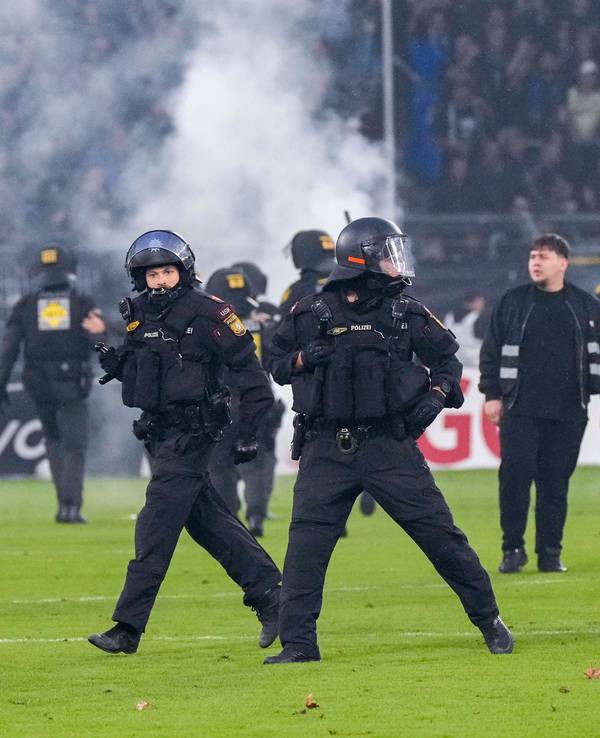 Polizisten sichern das Spielfeld nach Pyroattacken von den Rängen.