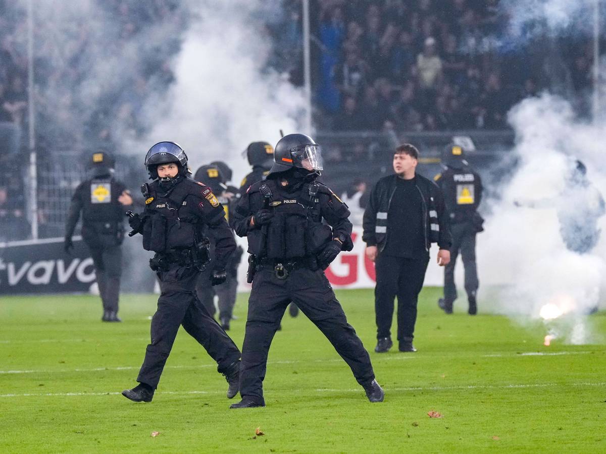 Polizisten sichern das Spielfeld nach Pyroattacken von den Rängen.