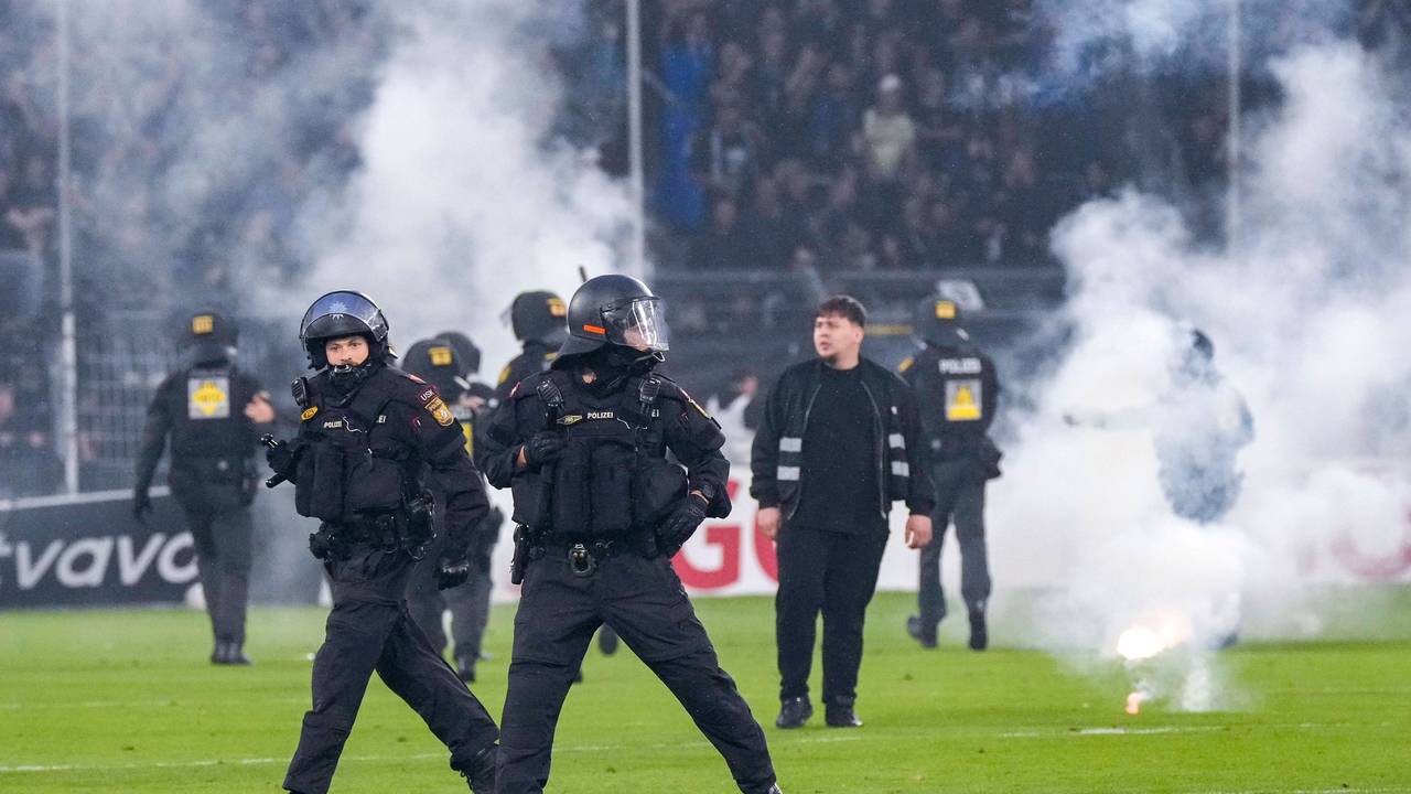 Polizisten sichern das Spielfeld nach Pyroattacken von den Rängen.