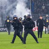 Polizisten sichern das Spielfeld nach Pyroattacken von den Rängen.