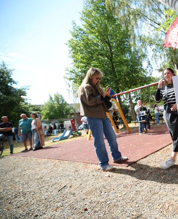 Eine Frau hält in Hürtgenwald ein Schild mit der Aufschrift „Der Wald brennt und Friedrich pennt“ vor dem Besuch von Bundeskanzler Merz in Hürtgenwald-Gey. Zwei Tage nach der vollständigen Löschung des verheerenden Waldbrands in der Eifel besucht Bundeskanzler das Gebiet, um den Helfern zu danken