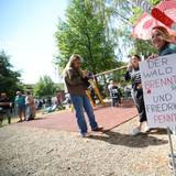 Eine Frau hält in Hürtgenwald ein Schild mit der Aufschrift „Der Wald brennt und Friedrich pennt“ vor dem Besuch von Bundeskanzler Merz in Hürtgenwald-Gey. Zwei Tage nach der vollständigen Löschung des verheerenden Waldbrands in der Eifel besucht Bundeskanzler das Gebiet, um den Helfern zu danken