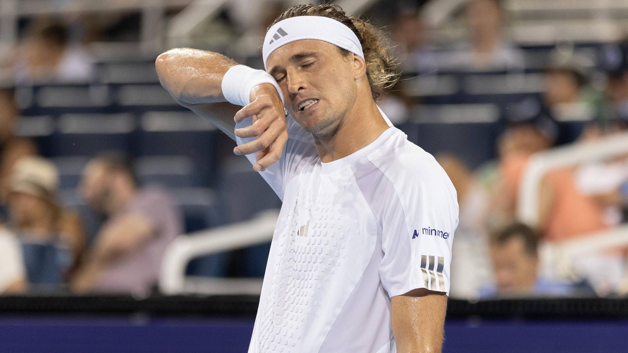 Alexander Zverev wischt sich mit dem Schweißband am Handgelenk über das Gesicht.