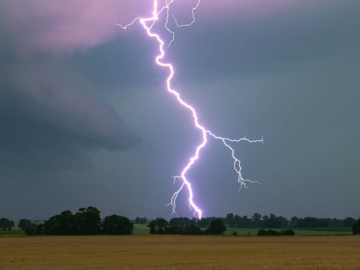 Ein Blitz leuchtet über einer Landschaft auf.