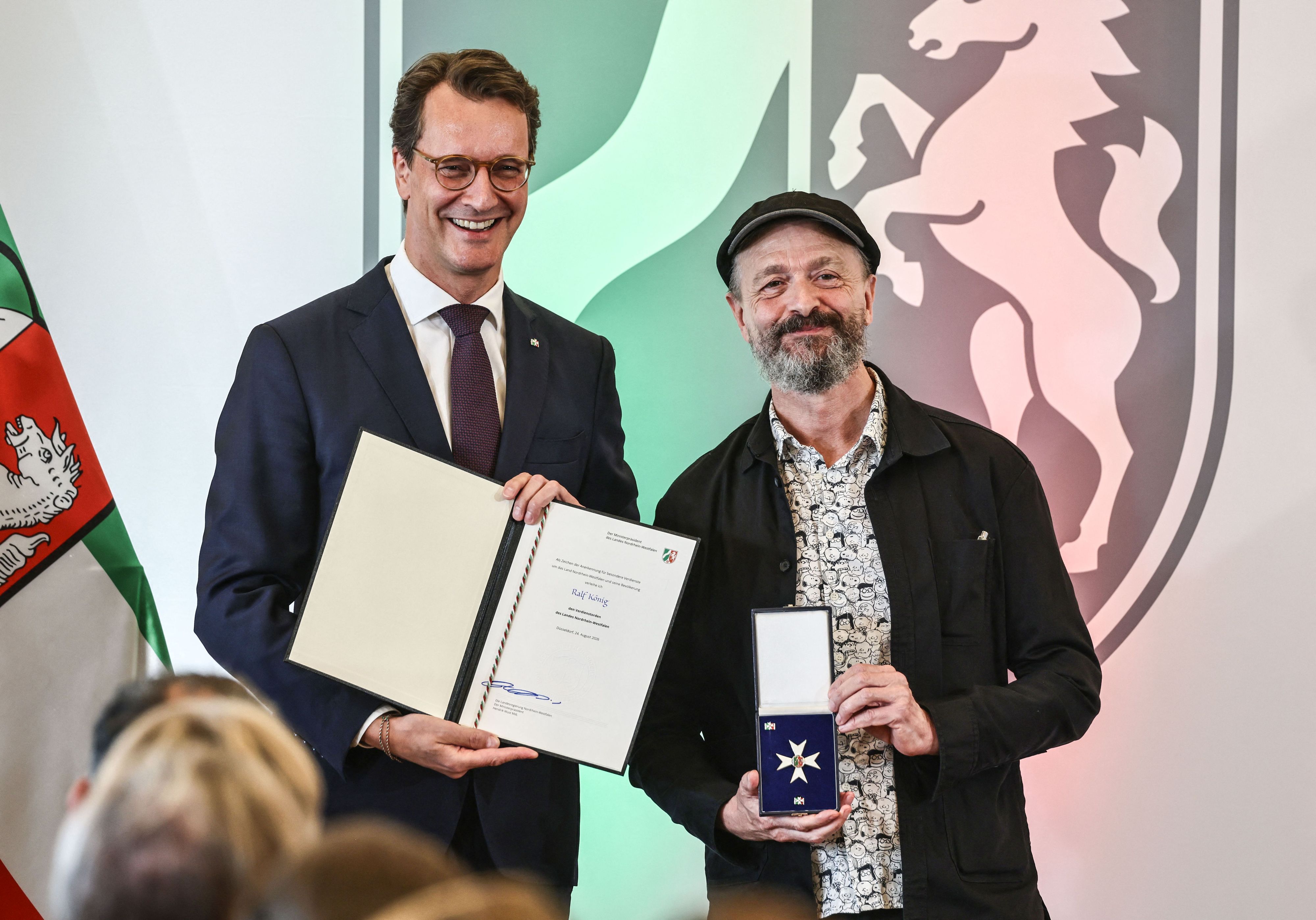 Ralf König nimmt von Hendrik Wüst den Landesverdienstorden entgegen.
