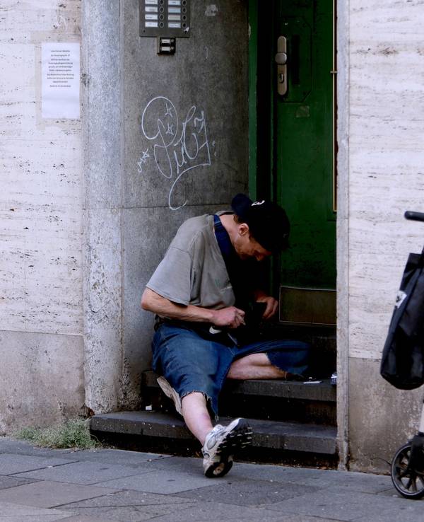 Ein Junkie setzt sich am Hauseingang einen Schuß.