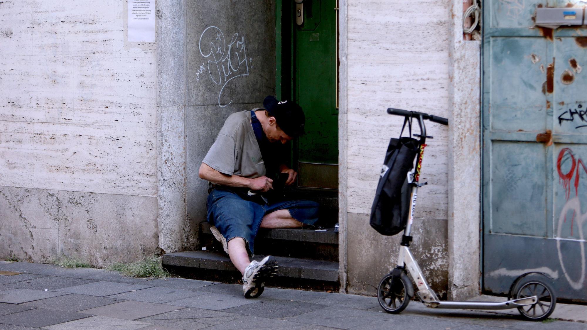 Ein Junkie setzt sich am Hauseingang einen Schuß.