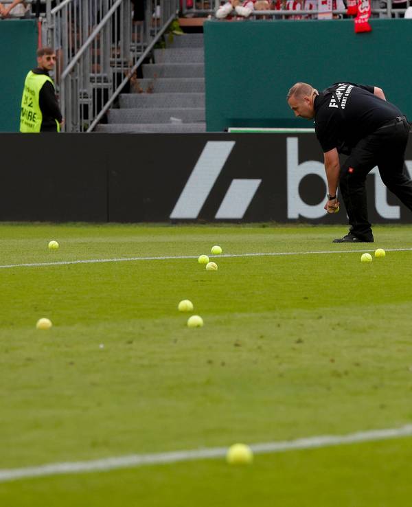 Ein Ordner sammelt Tennisbälle auf.