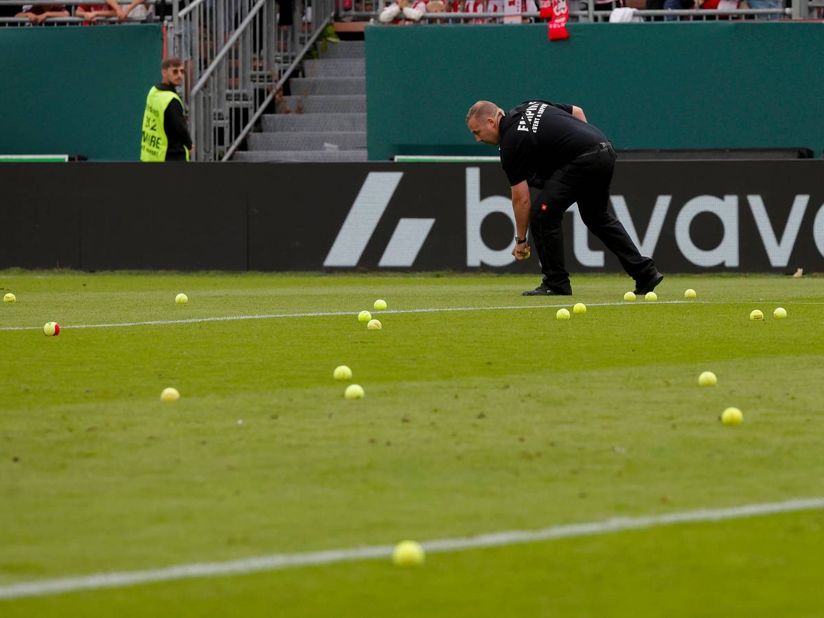 Ein Ordner sammelt Tennisbälle auf.