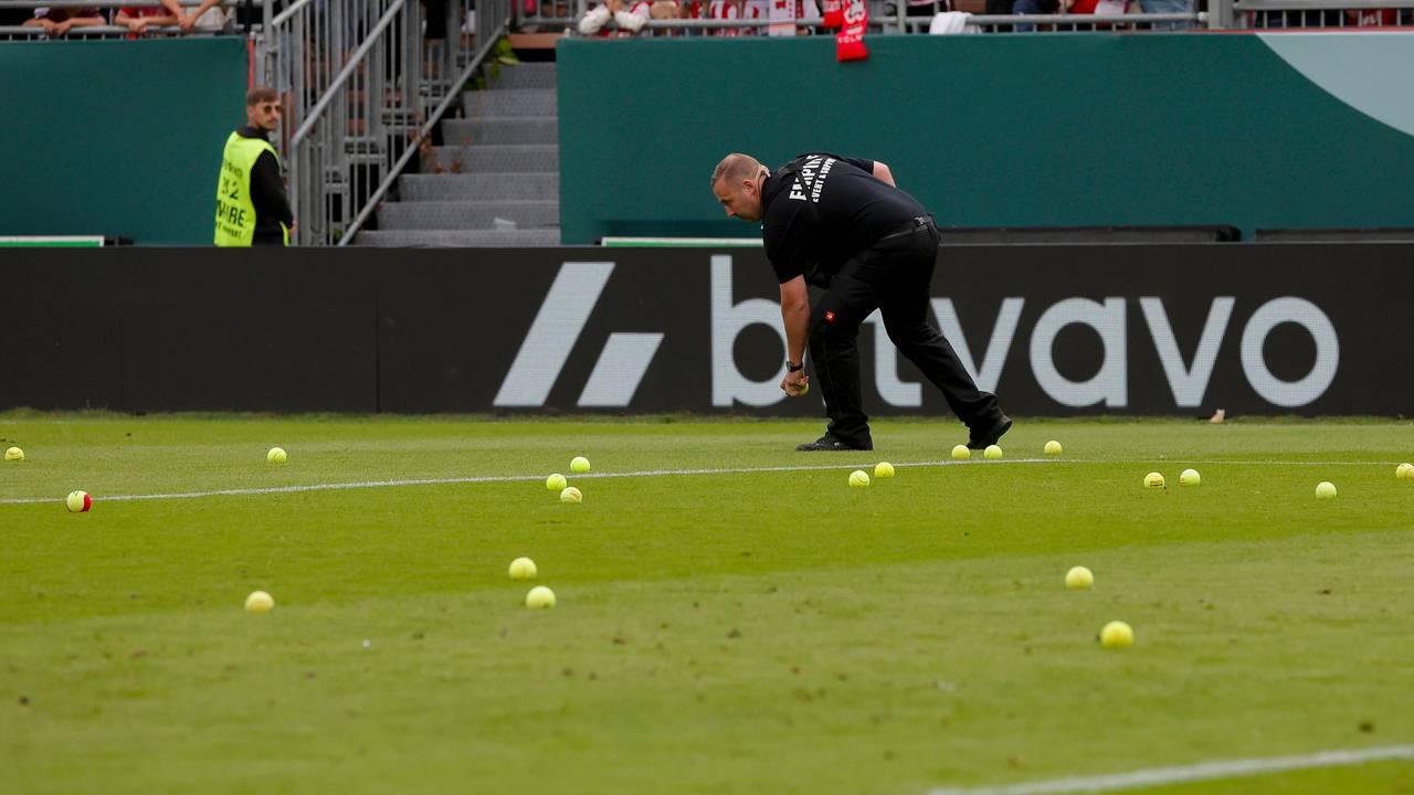 Ein Ordner sammelt Tennisbälle auf.