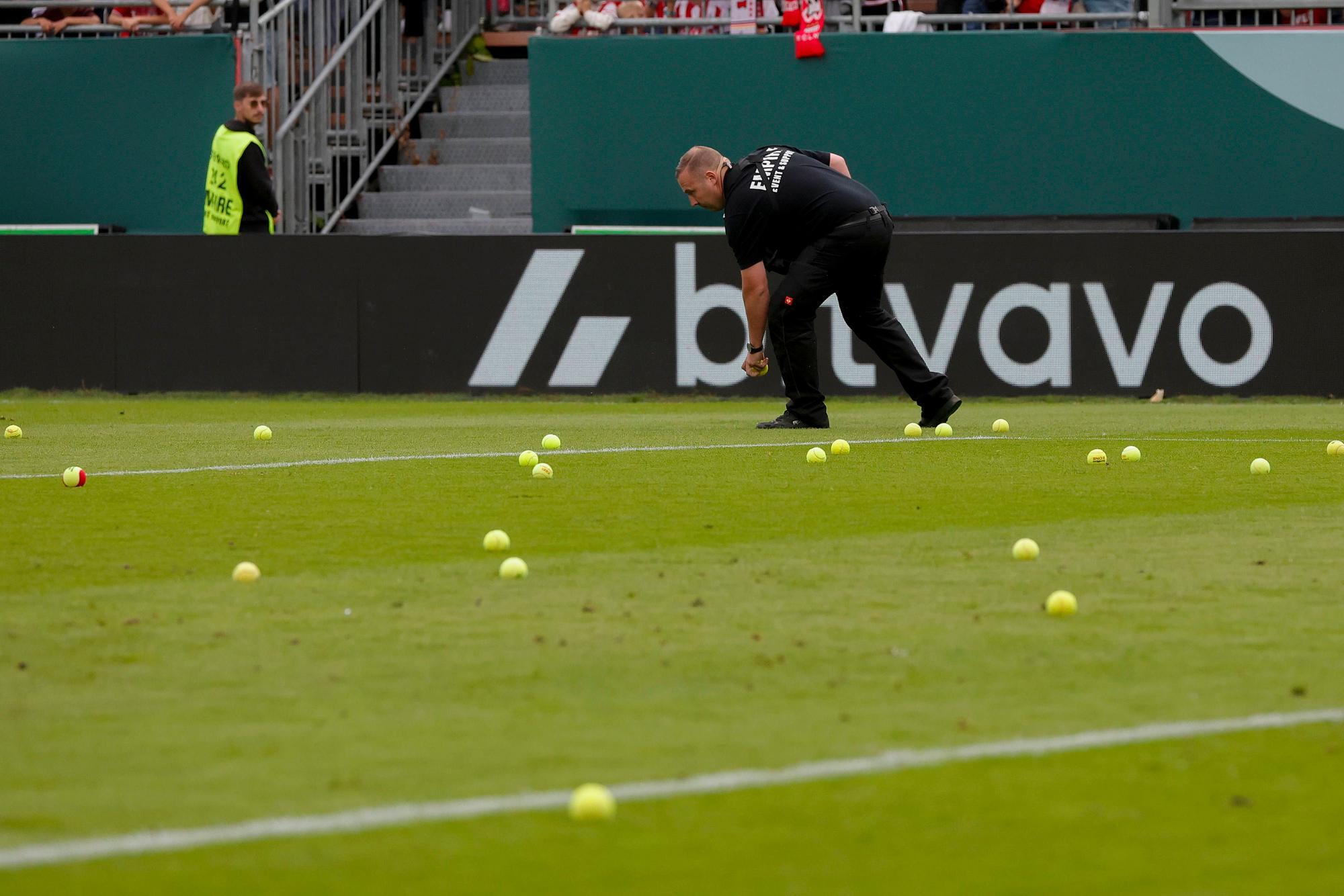 Ein Ordner sammelt Tennisbälle auf.