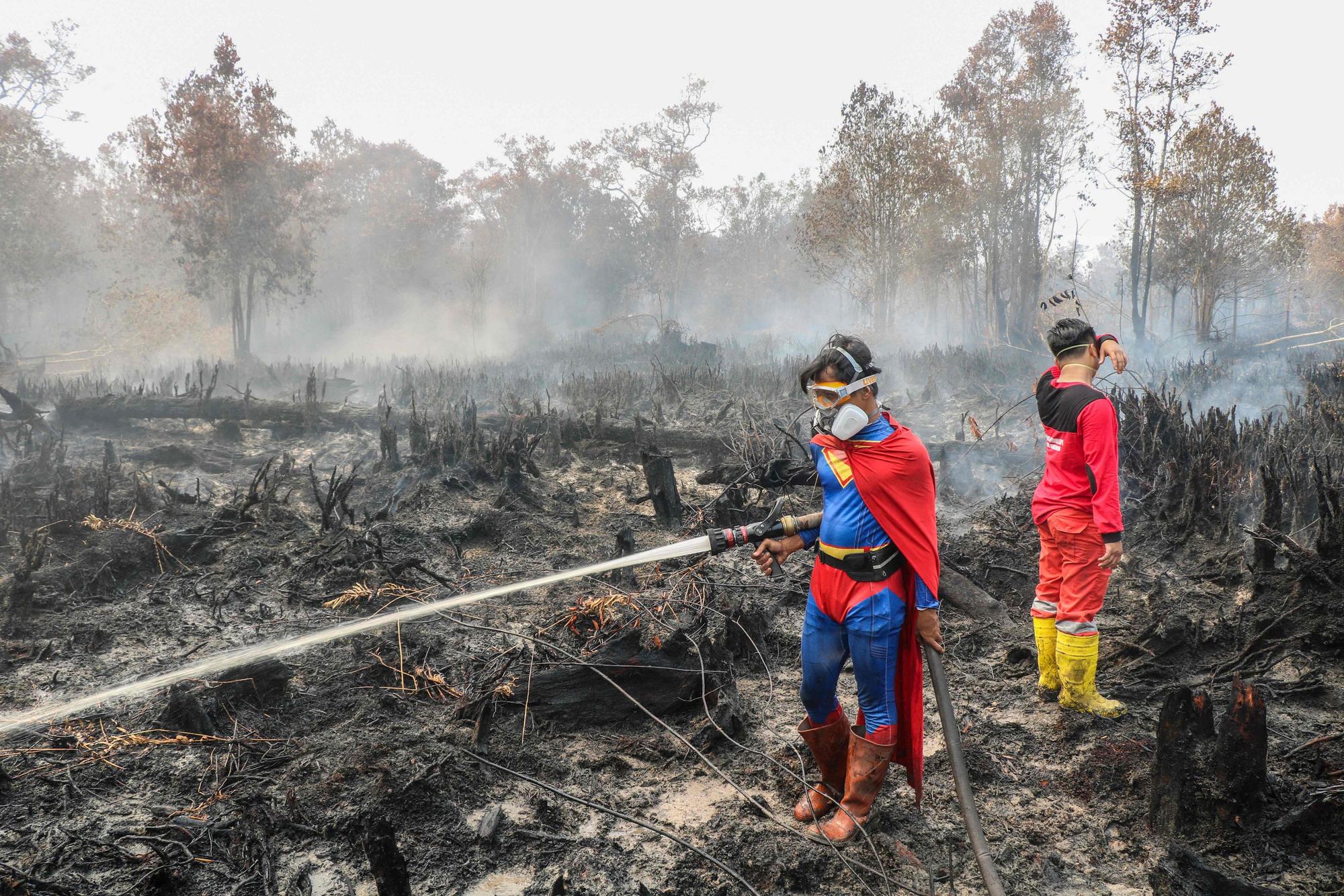 Der Student Rudiansyah (L) trägt ein Superman-Kostüm während des Löscheinsatzes.