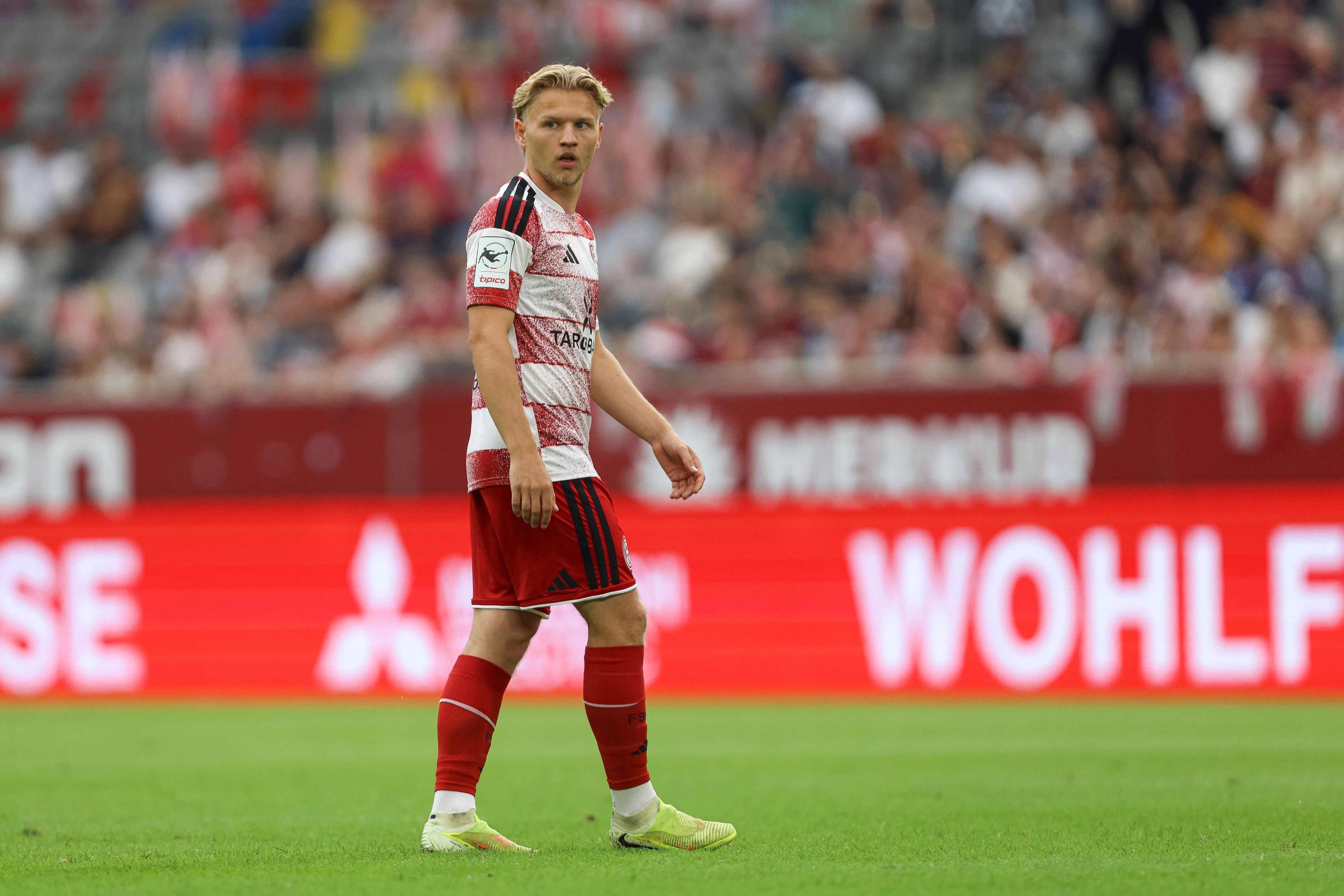 Andreas Müller steht auf dem Rasen und blickt zur Seite. Er trägt ein rot-weißes Trikot von Fortuna Düsseldorf.