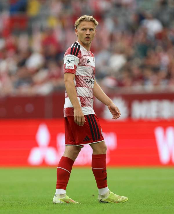 Andreas Müller steht auf dem Rasen und blickt zur Seite. Er trägt ein rot-weißes Trikot von Fortuna Düsseldorf.