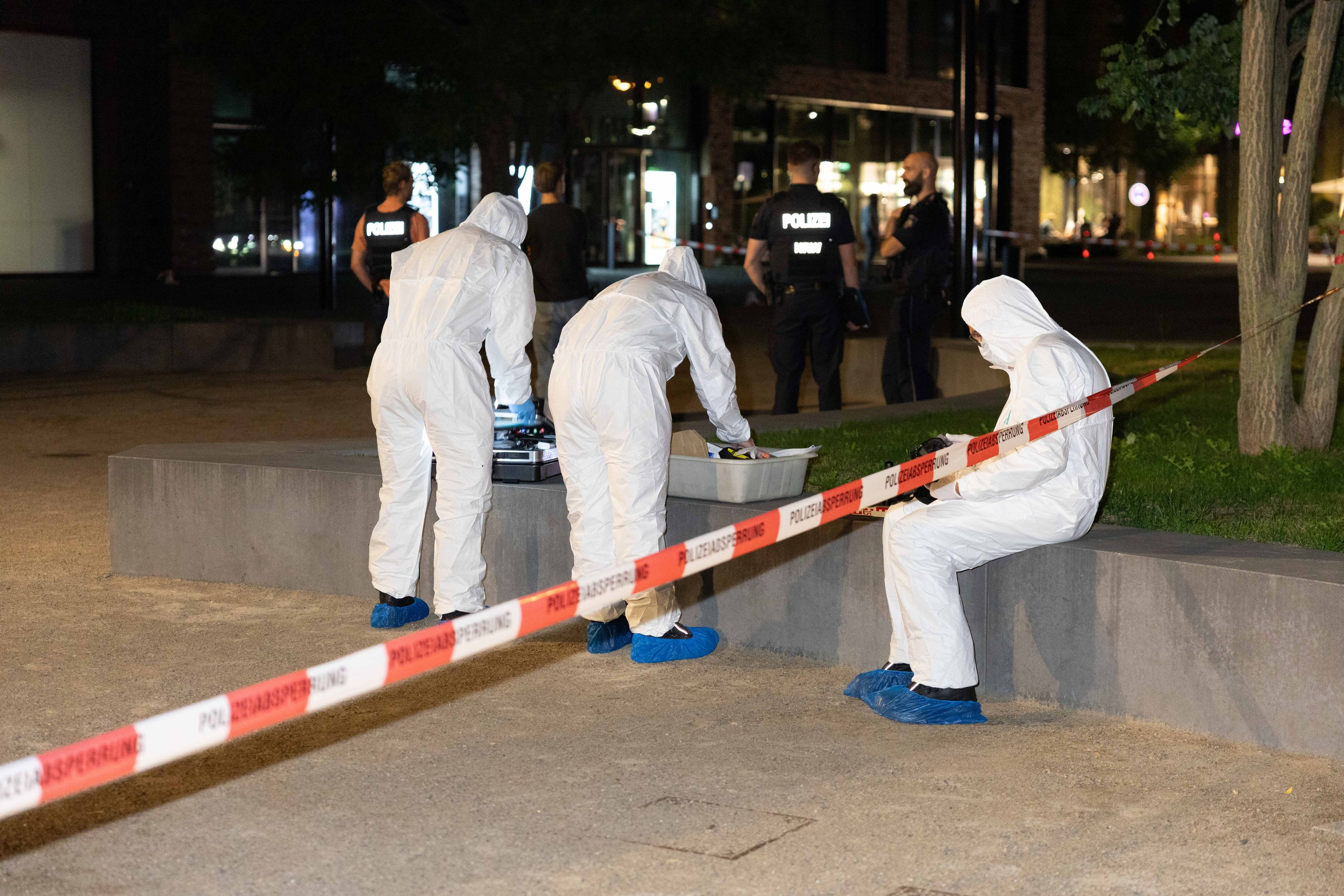 Drei Personen in Schutzanzügen sind an einem Tatort im Einsatz.