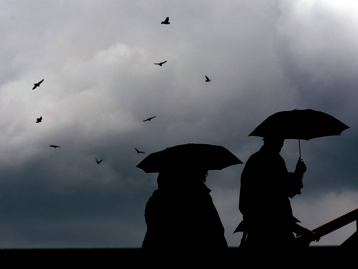 Menschen laufen mit Regenschirmen durch die Kölner Innenstadt (Archivbild).