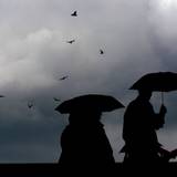 Menschen laufen mit Regenschirmen durch die Kölner Innenstadt (Archivbild).