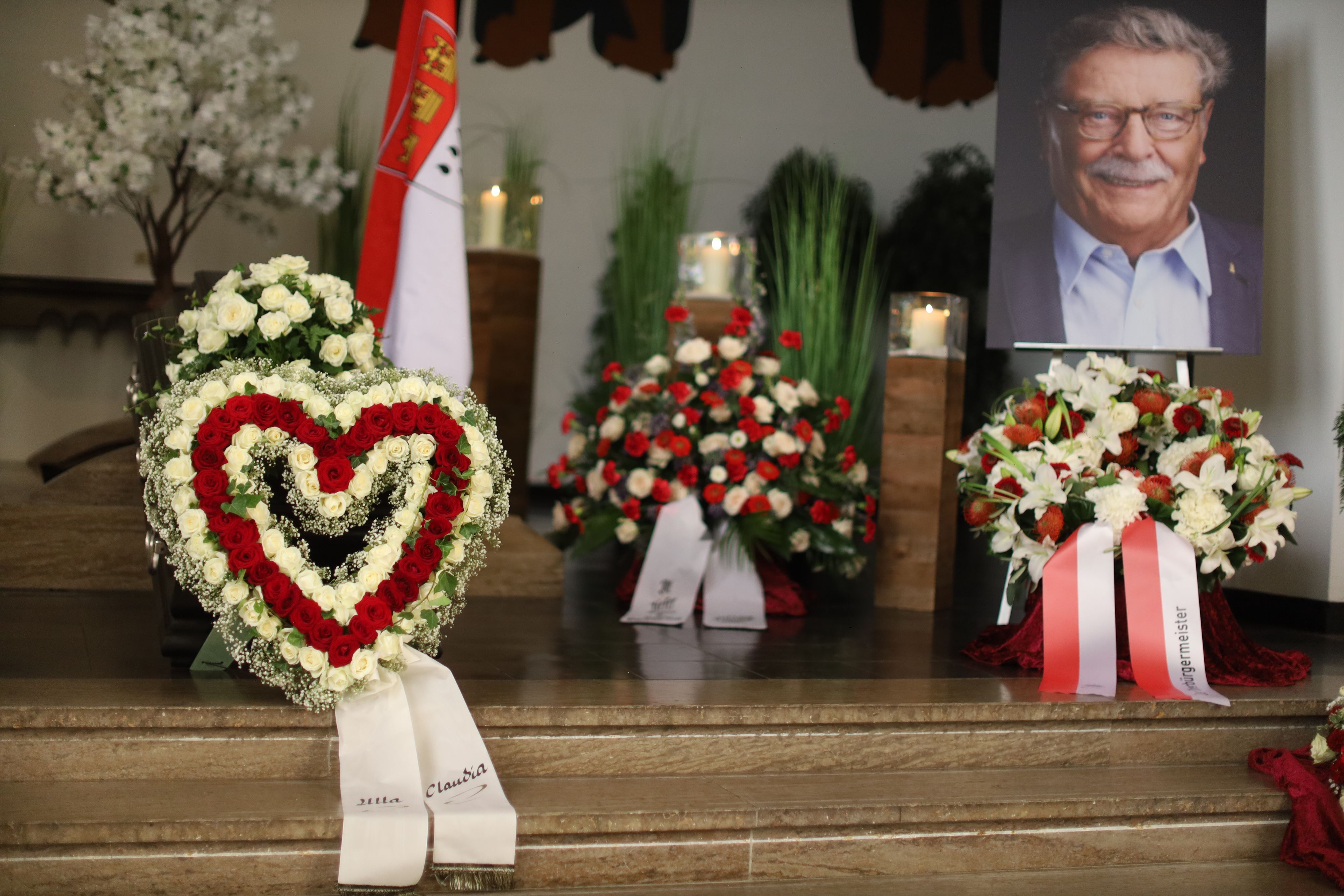 Ein Herz aus Blumen und zahlreiche Kränze umgeben den Sarg von Fritz Schramma.