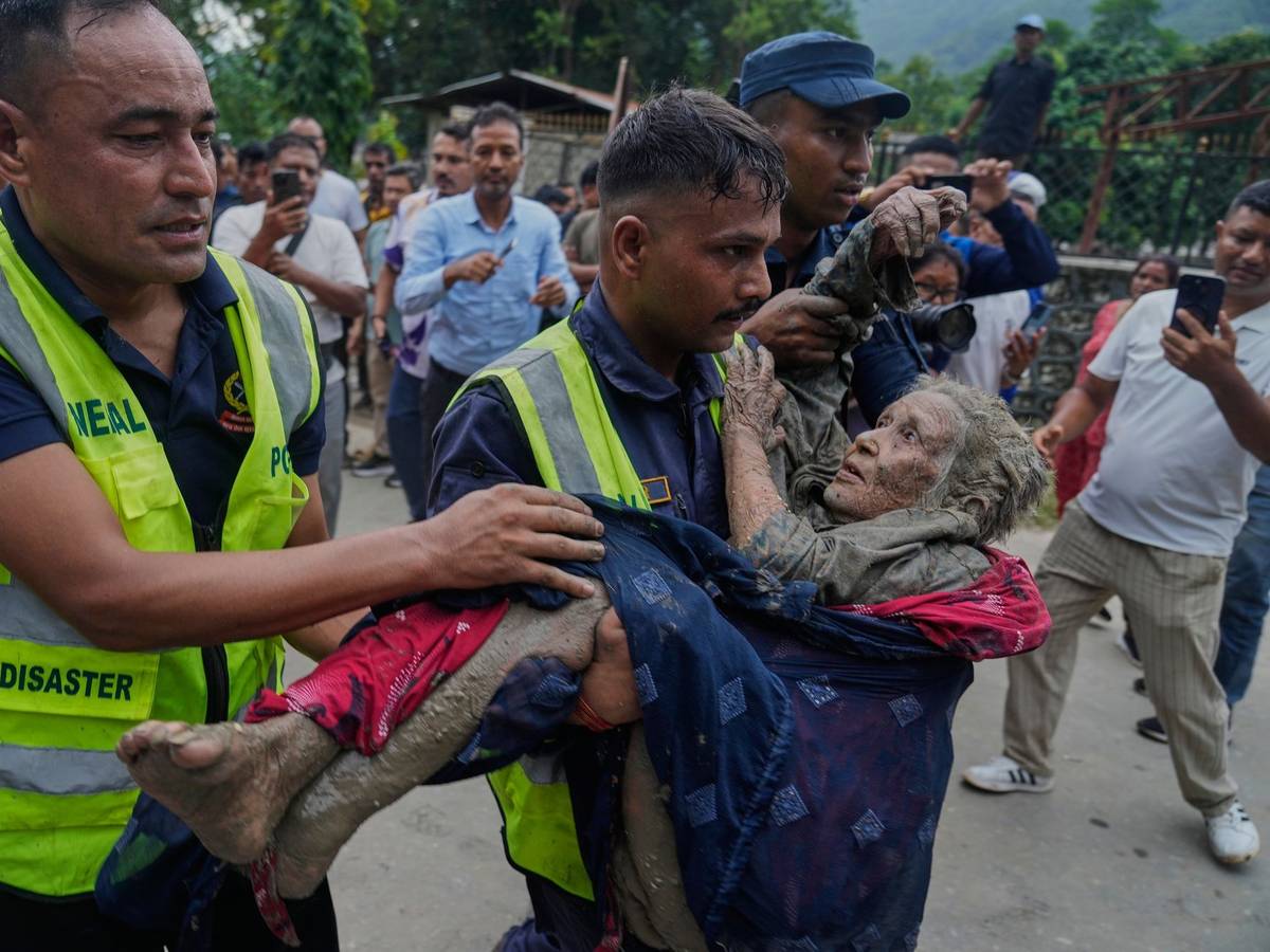 Sturzflut an Grenze zwischen China und Nepal: Rettungskräfte tragen eine Frau aus dem Schlamm.