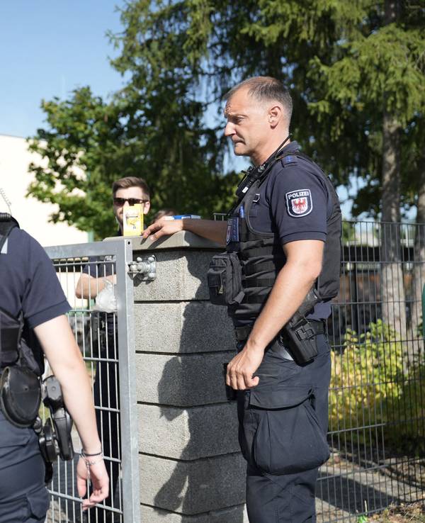 Zwei Polizisten und ein Polizist stehen vor einer Schule.
