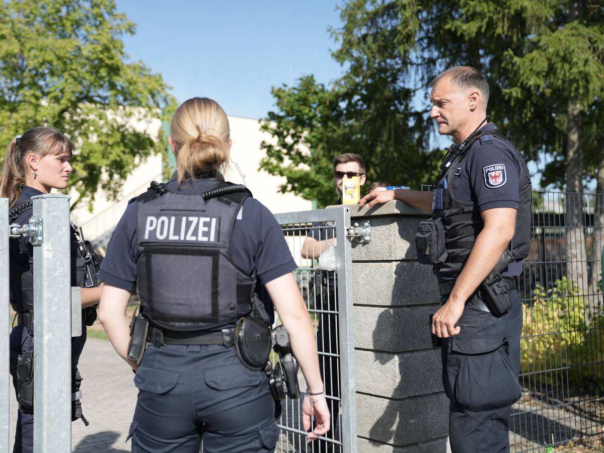 Zwei Polizisten und ein Polizist stehen vor einer Schule.