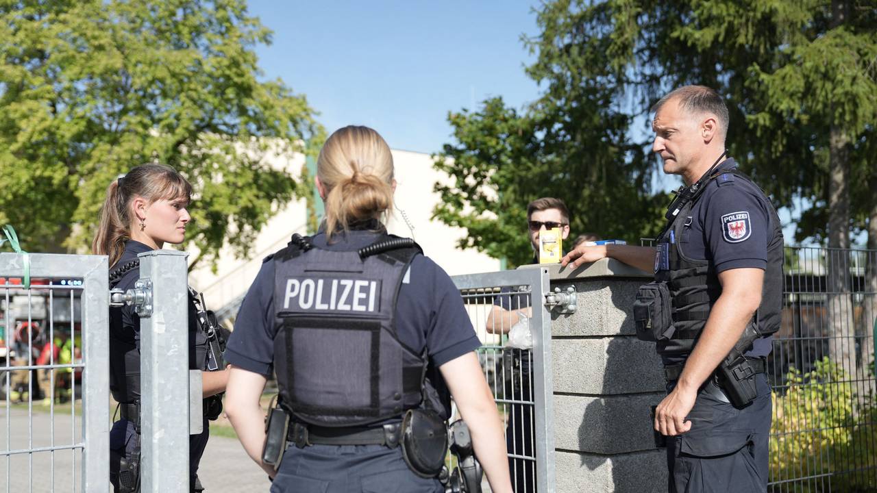 Zwei Polizisten und ein Polizist stehen vor einer Schule.