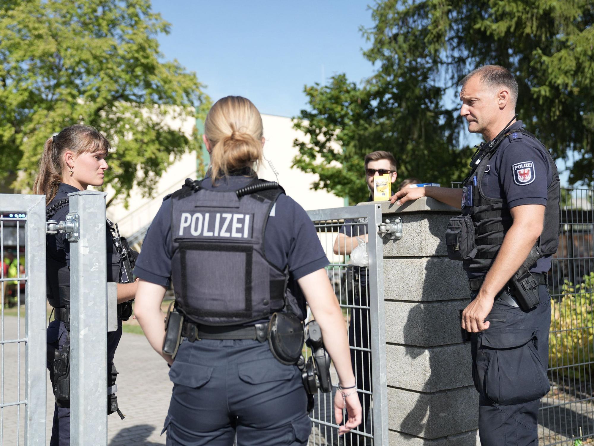 Zwei Polizisten und ein Polizist stehen vor einer Schule.