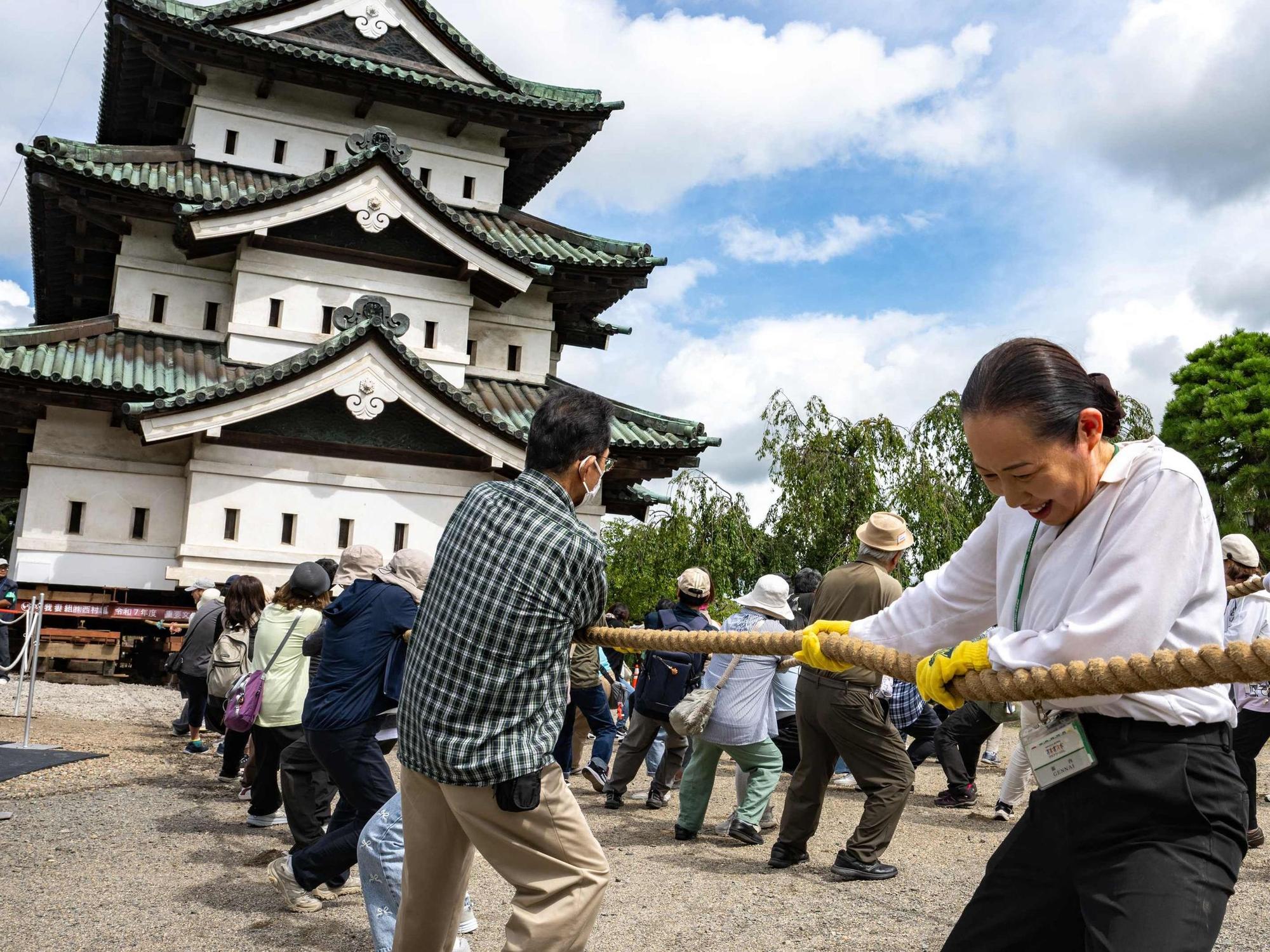 Nach den Restaurierungsarbeiten in Hirosaki in der Präfektur Aomori ziehen Freiwillige am 26. August 2026 einen Teil der Burg Hirosaki mit Seilen an ihren ursprünglichen Standort zurück.