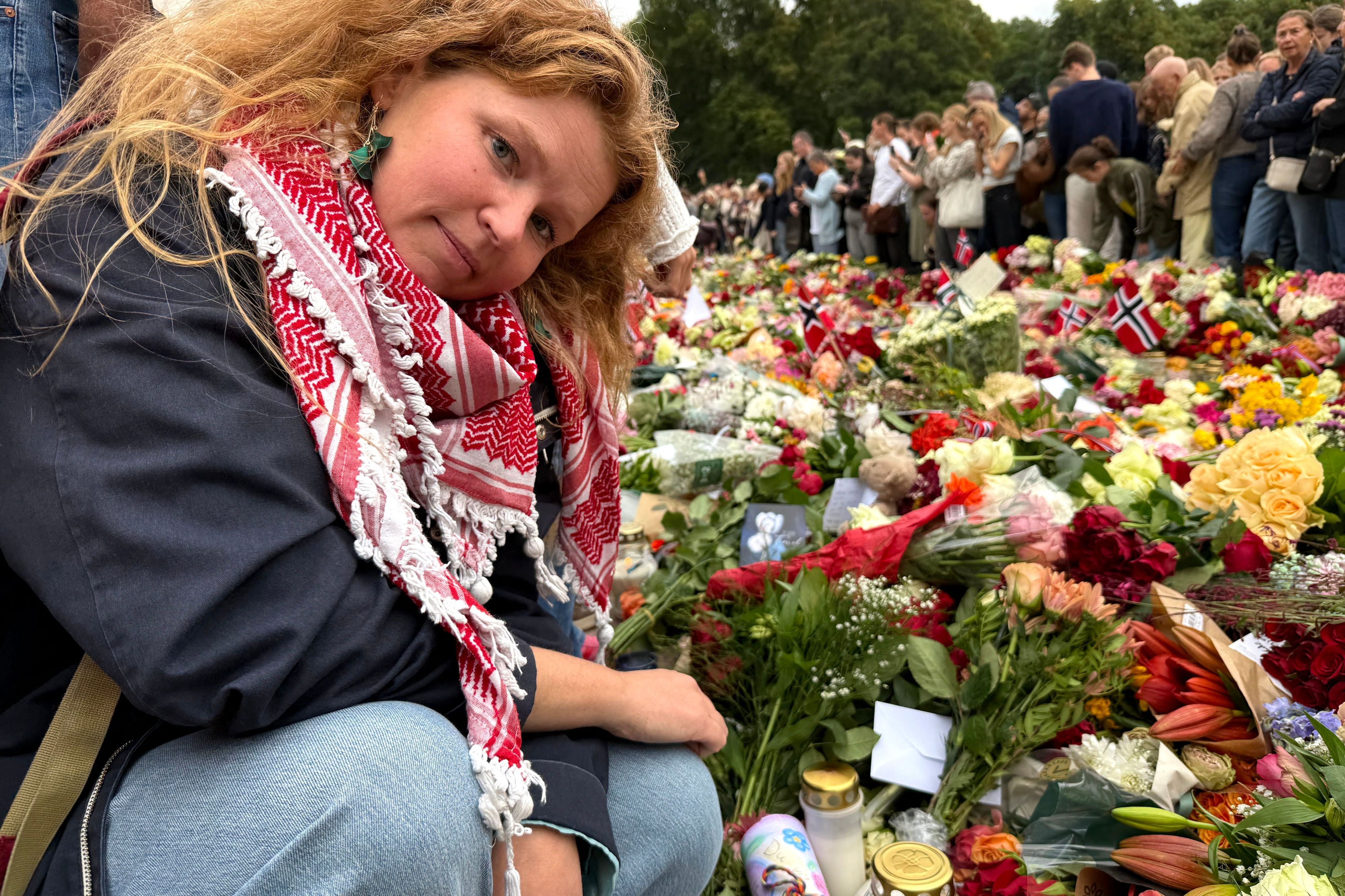 Die Lehrerin Ida Berg Knudsen legt Briefe, die ihre Schülerinnen und Schüler für den verstorbenen König Harald geschrieben haben, zwischen den vor dem Königlichen Schloss Oslo abgelegten Blumen ab.