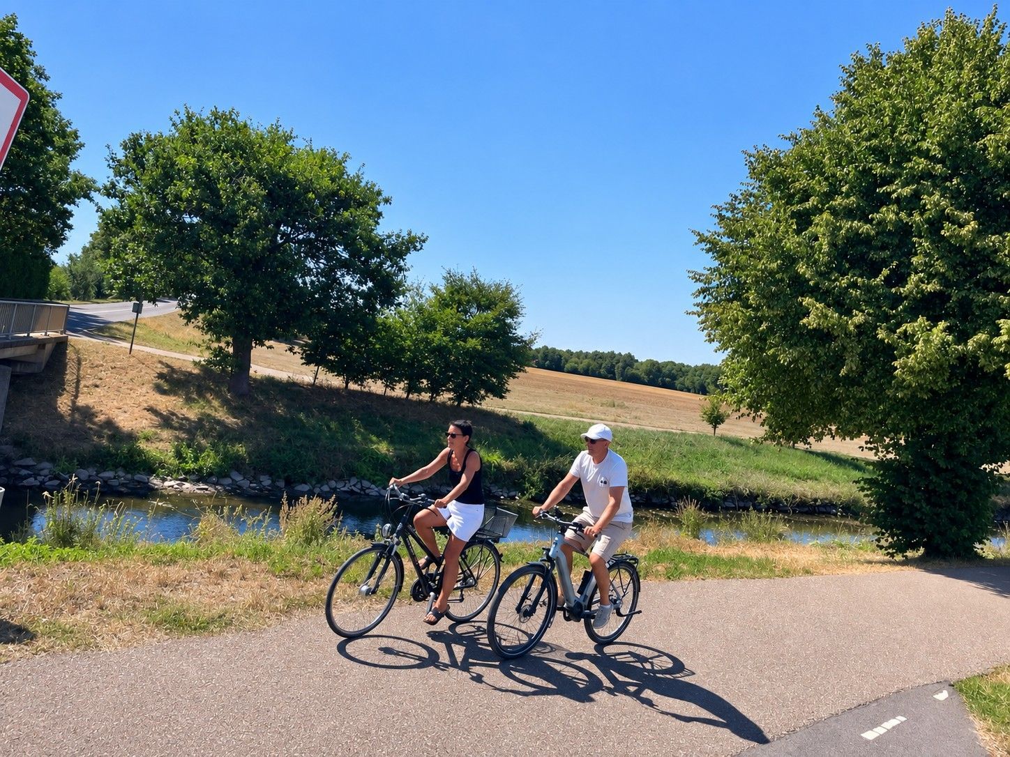 Zwei Radfahrer fahren durch eine sommerliche Flusslandschaft