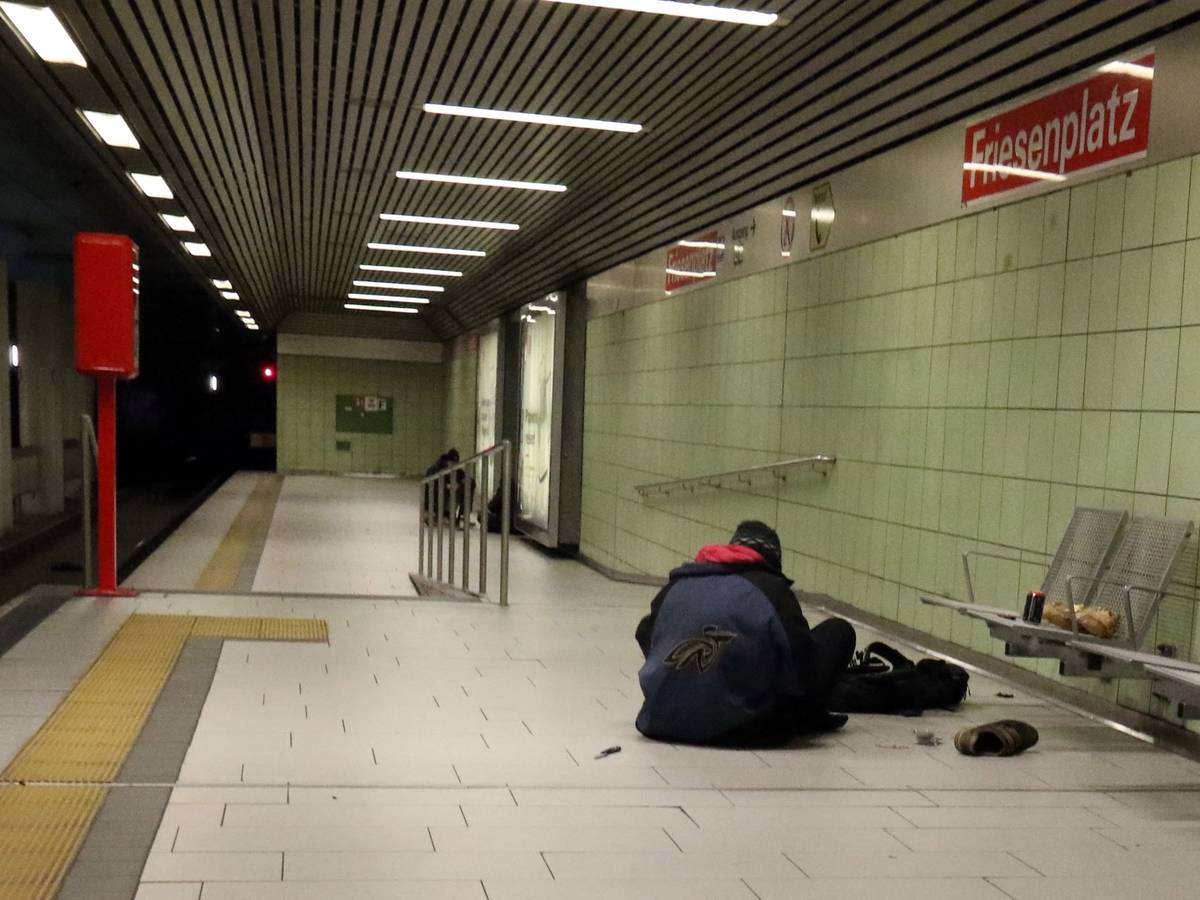 Eine Person sitzt in einer U-Bahnhaltestelle auf dem Boden.