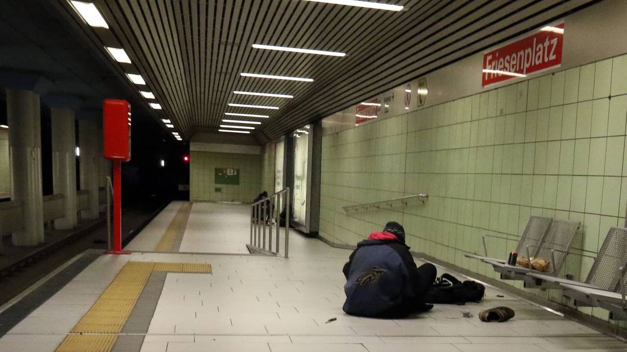 Eine Person sitzt in einer U-Bahnhaltestelle auf dem Boden.