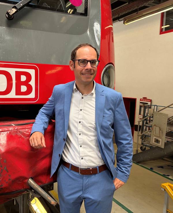 Markus Kaupper stützt einen Arm auf eine DB-Bahn.