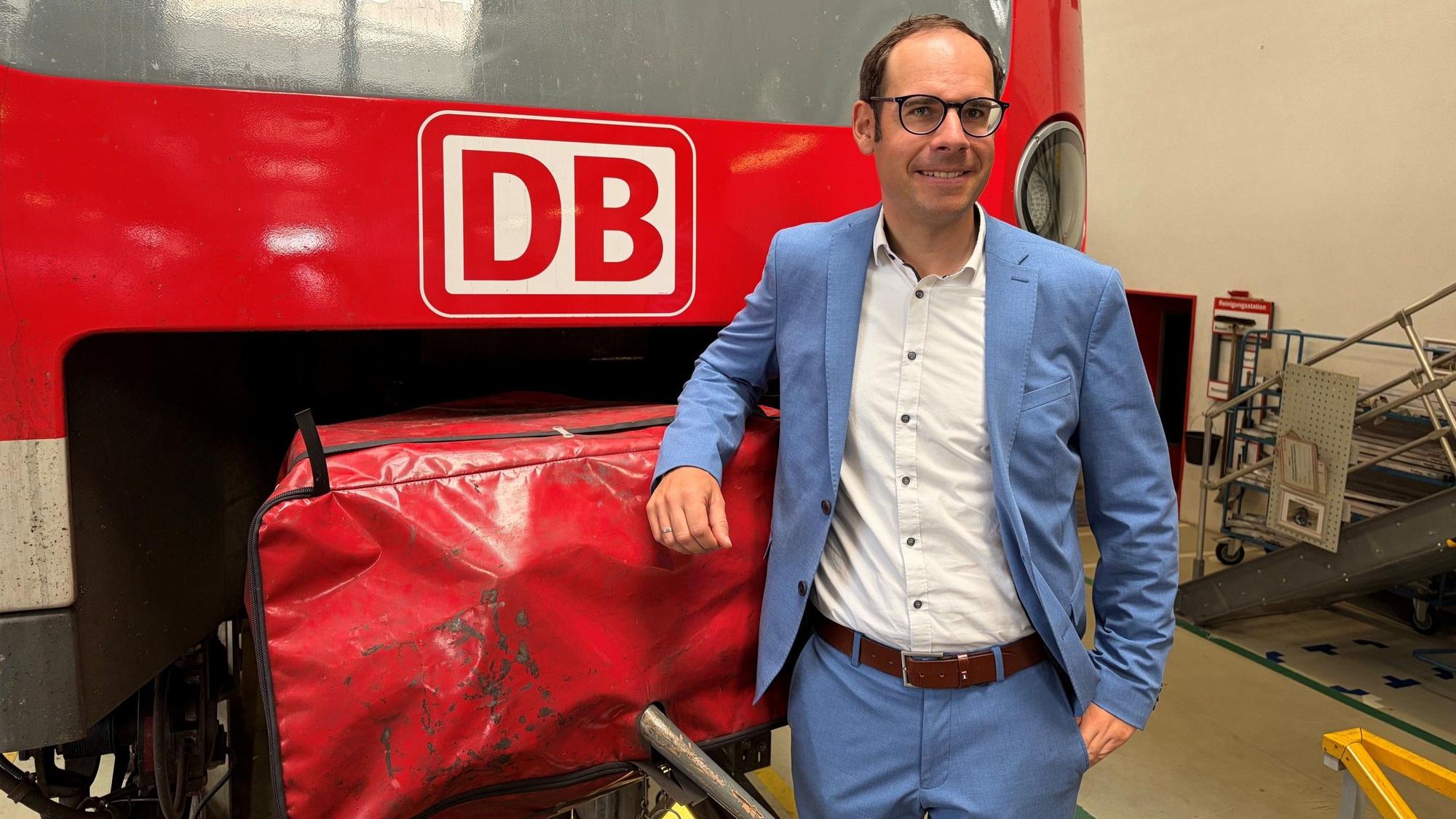Markus Kaupper stützt einen Arm auf eine DB-Bahn.