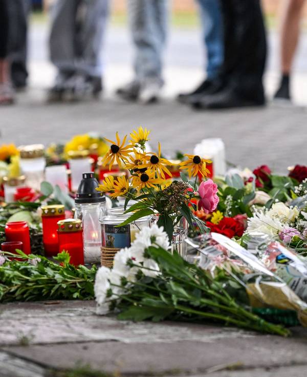 Blumen und Kerzen liegen vor einer Schule im Landkreis Oder-Spree. Dort wurden eine 18-jährige Schülerin und ein 30-jähriger Kita-Erzieher getötet.
