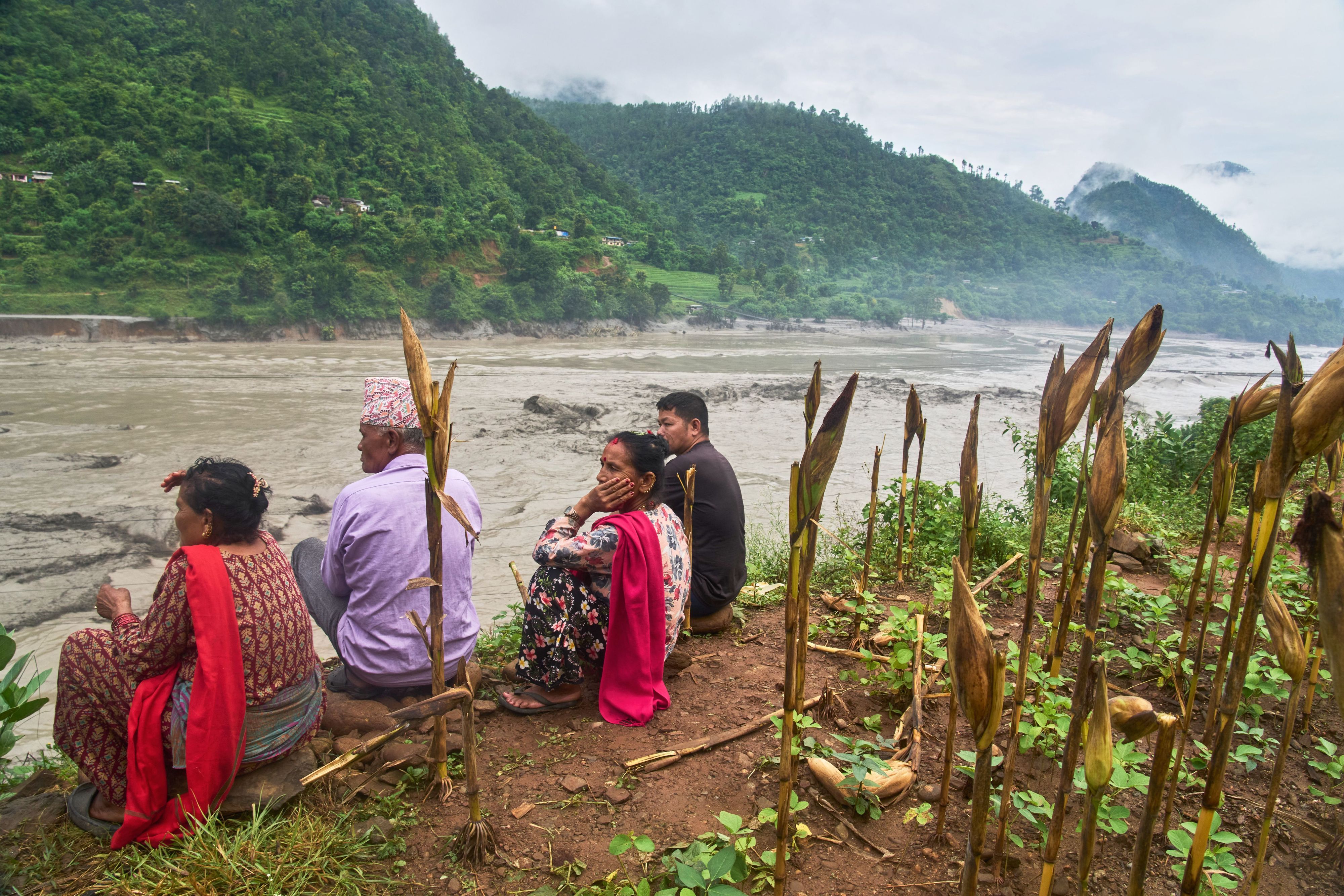 Menschen beobachten von einem Feld am Ufer des Flusses Trishuli das reißende Wasser.